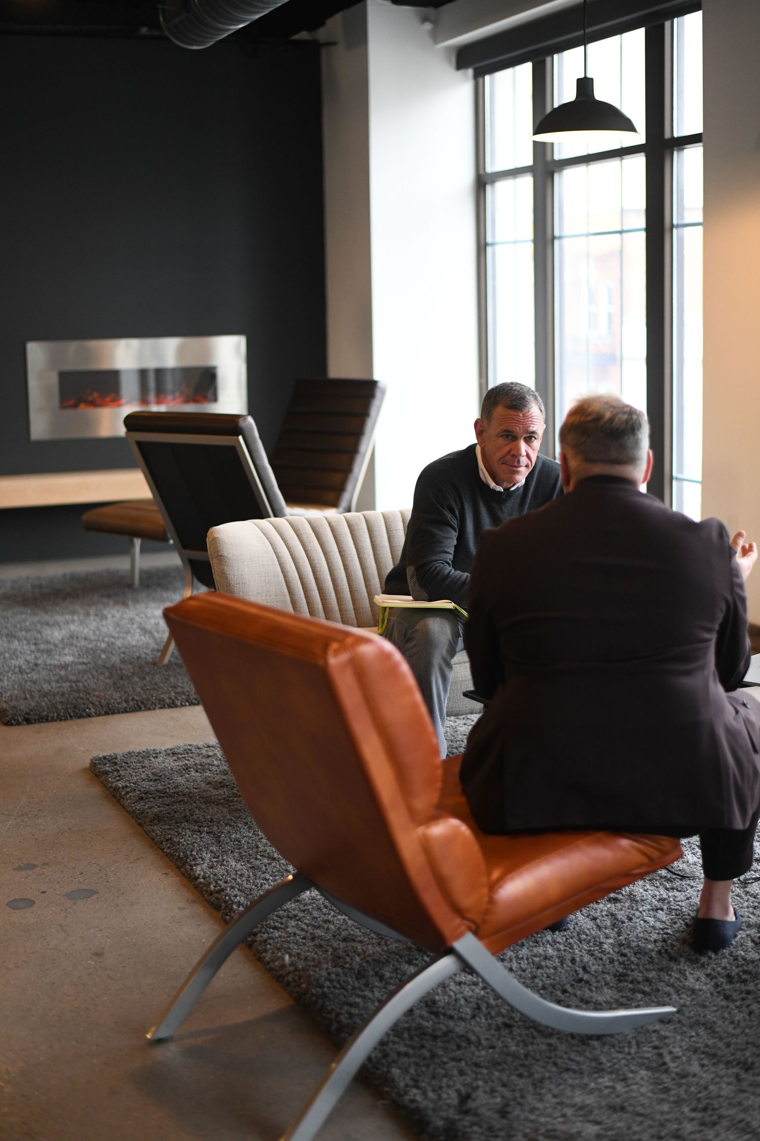 Modern office lounge with leather Barcelona chairs and large windows.