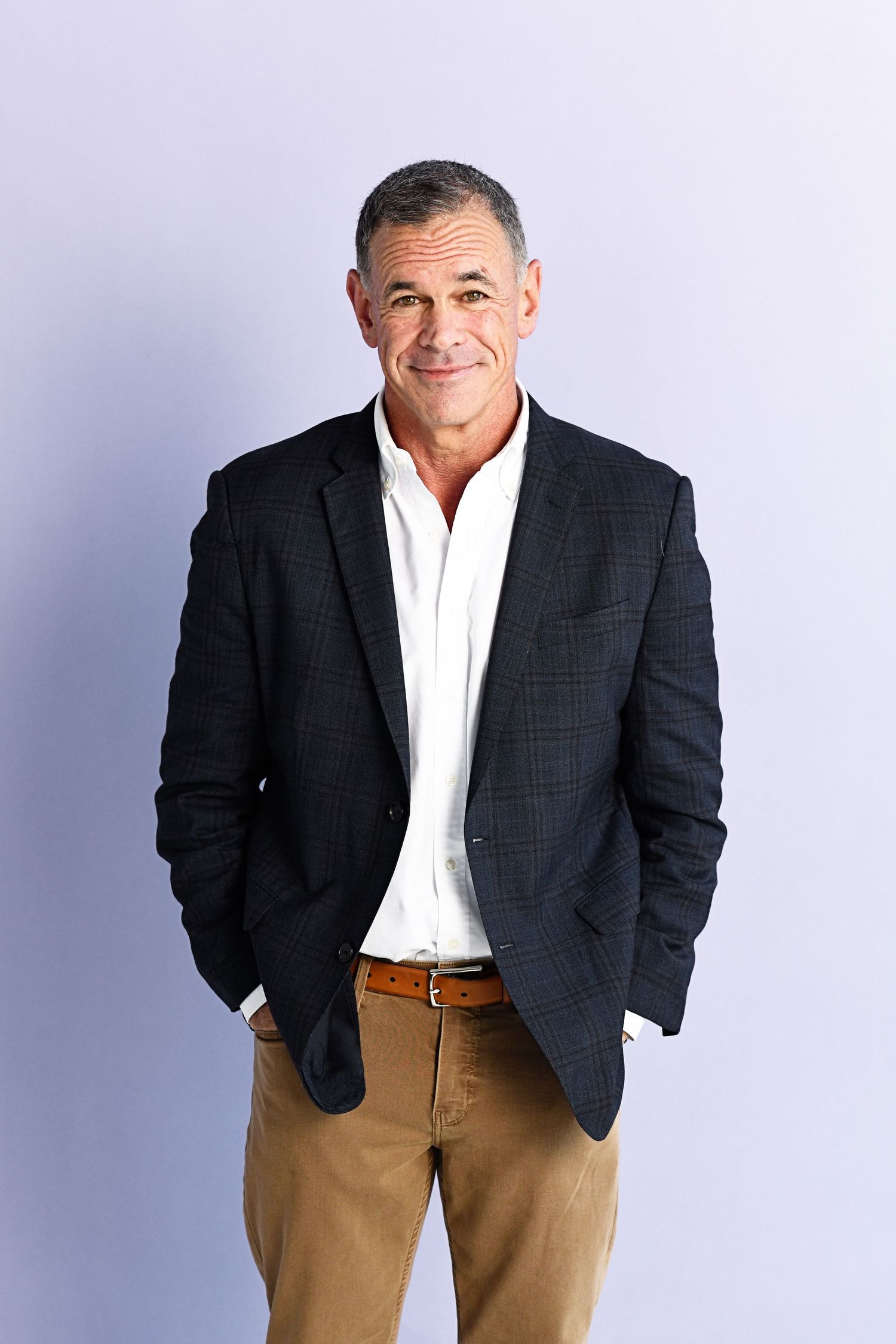 Professional headshot sequence of person in navy blazer and khaki pants against blue background.