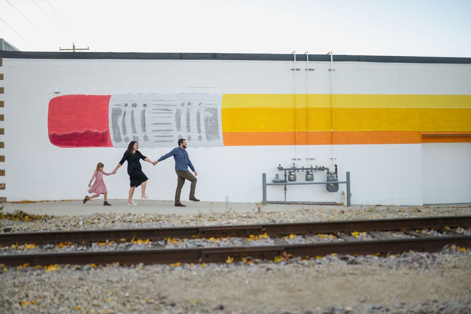 Colorful pencil mural painted on white wall near railroad tracks.