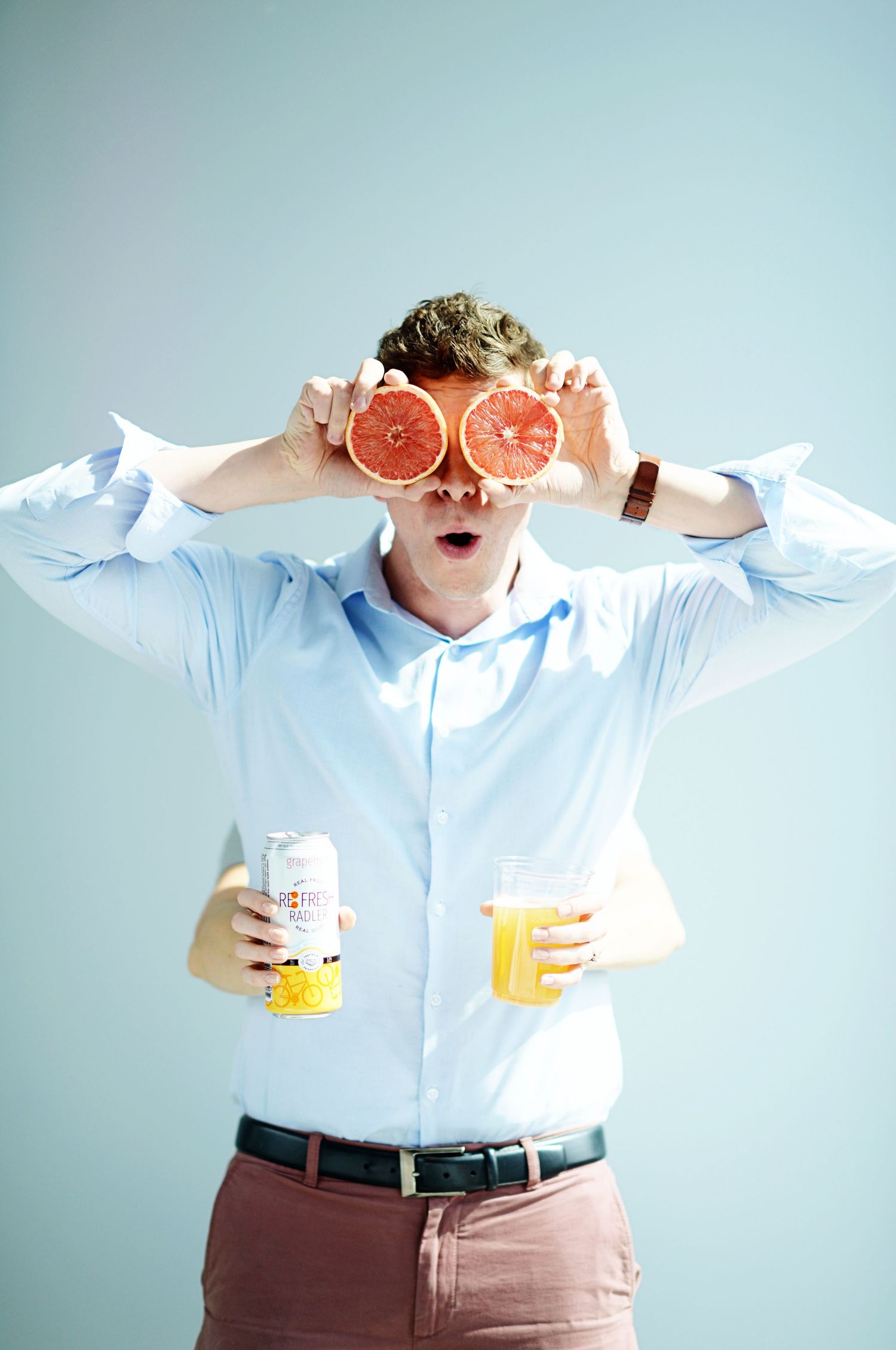 Playful setup with citrus fruits and beverages against light blue background.