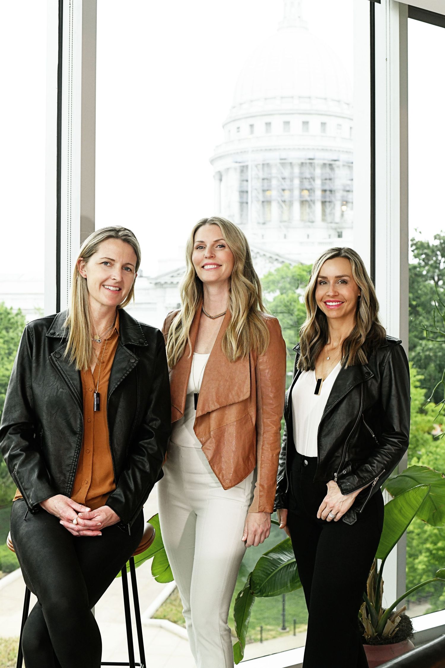 Professional group photo series of team in business attire by window with capitol building view.