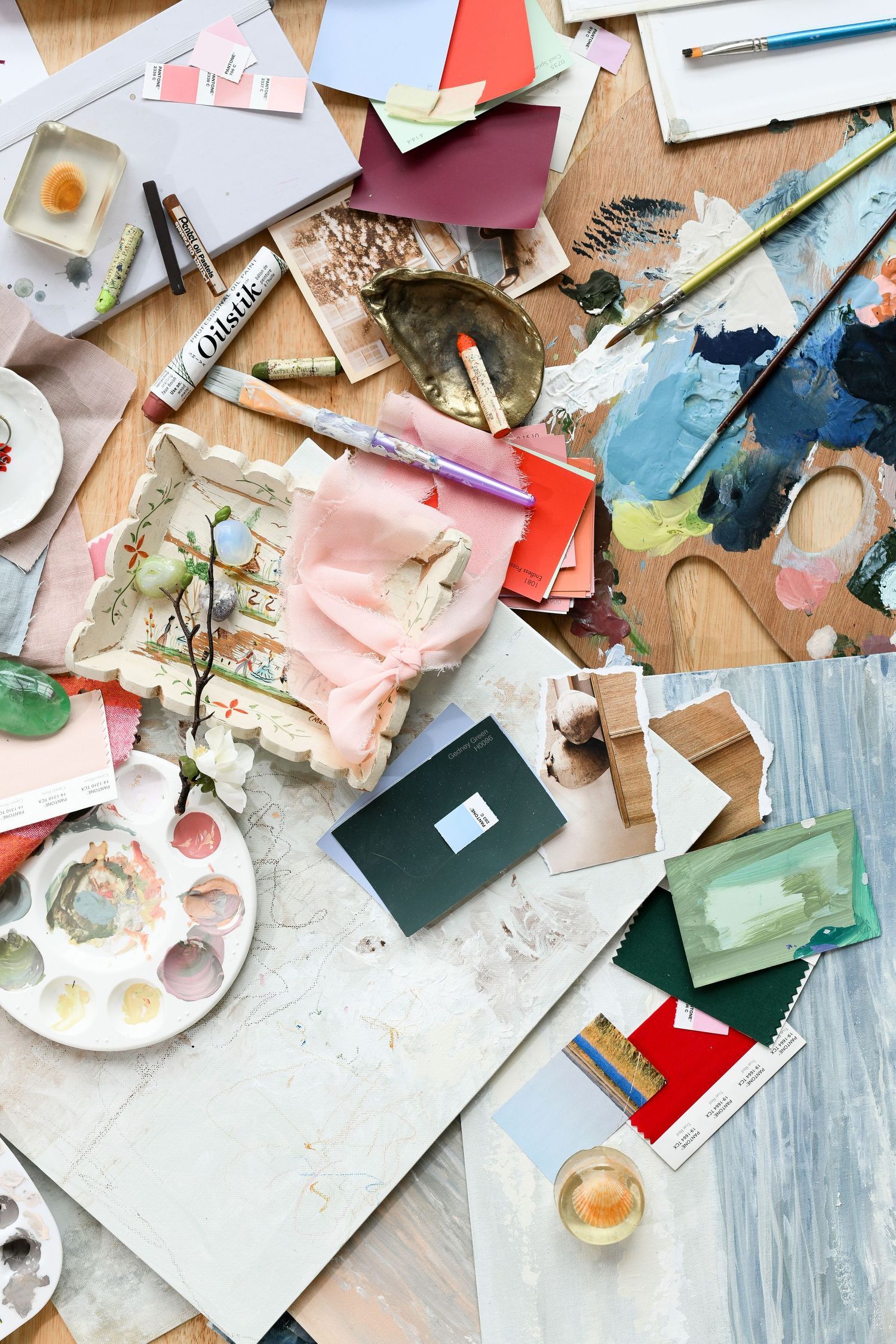 Messy collection of art supplies and paper scraps scattered across wooden surface.
