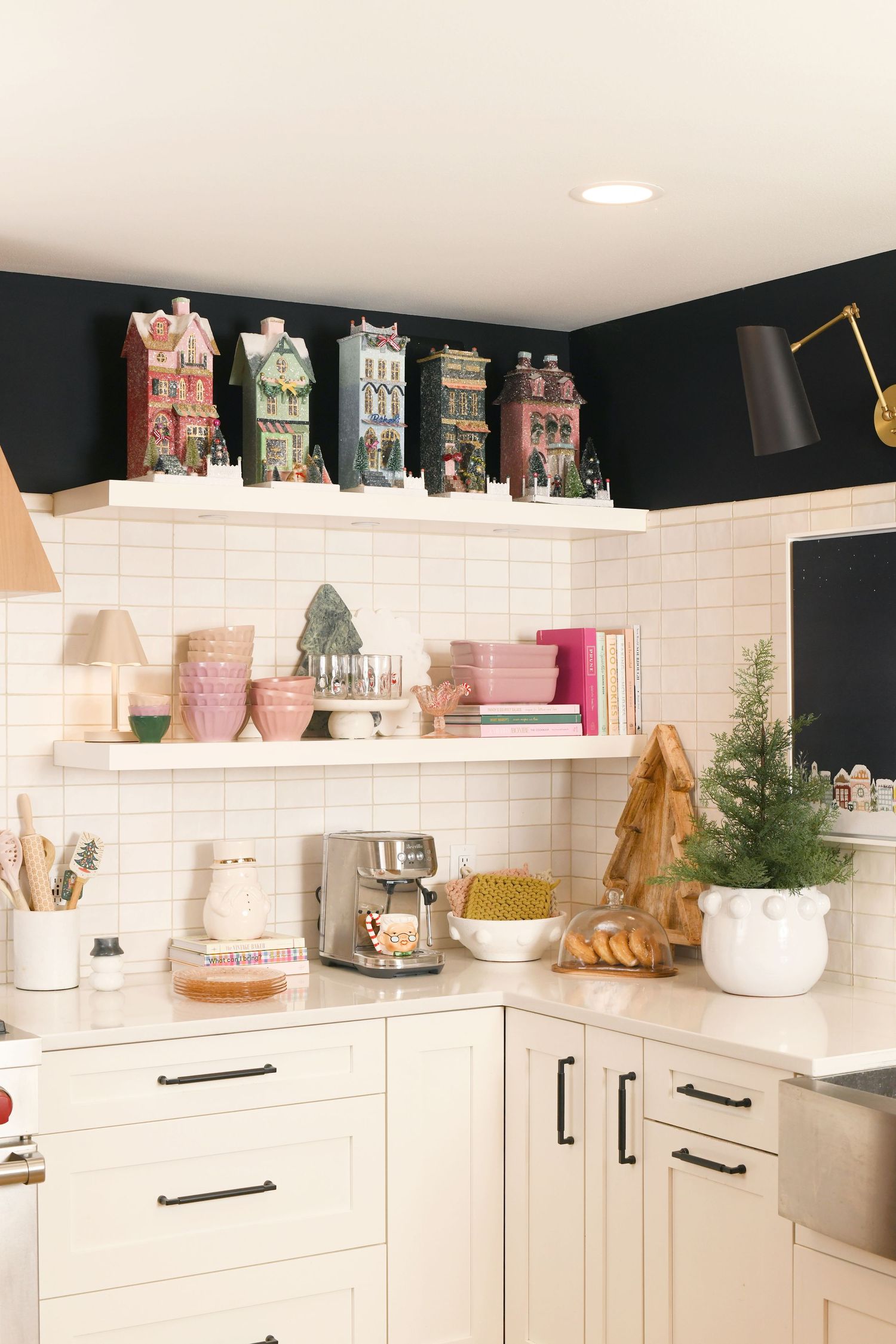 White kitchen corner with vintage house collectibles displayed on floating shelves against dark walls.