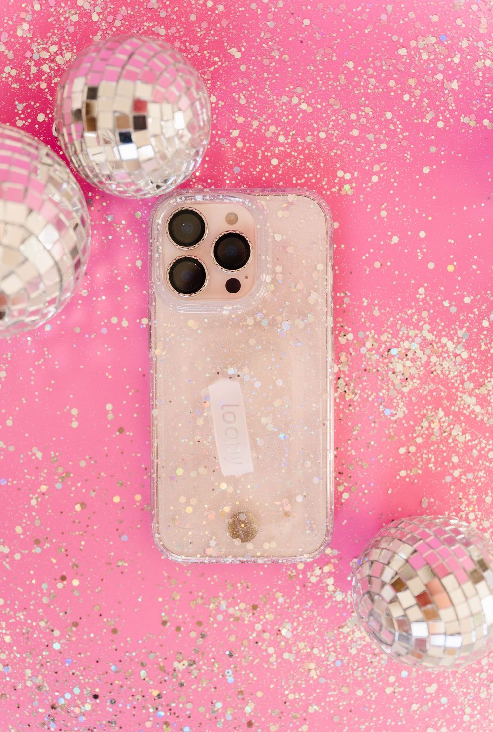 Disco balls and glitter sparkle against a pink background creating a festive party atmosphere.