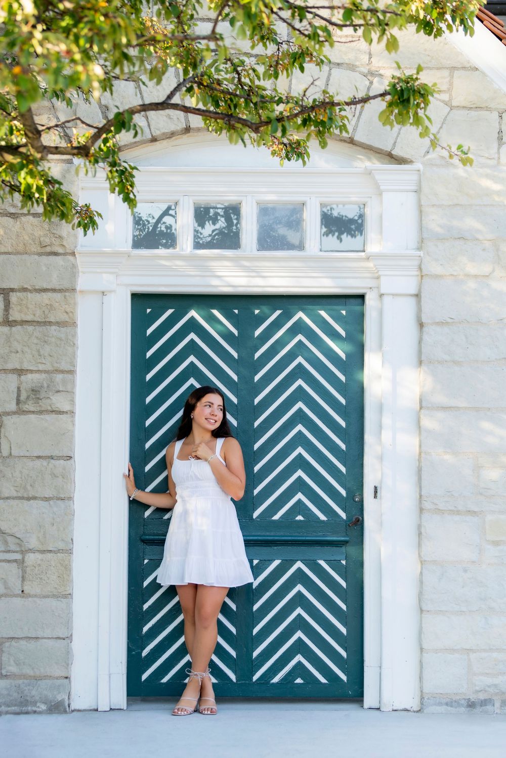 White stone building exterior with teal geometric patterned garage doors and overhanging tree branches.