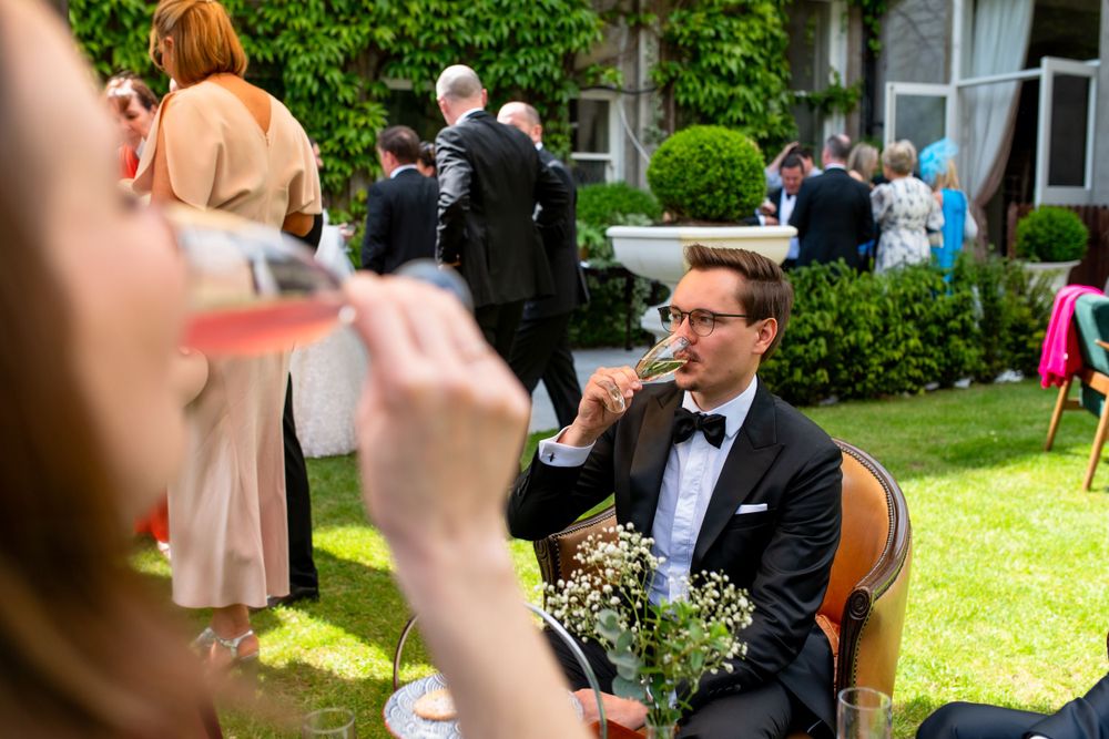 Outdoor wedding scene with formal attire and flower bouquets in a garden setting.
