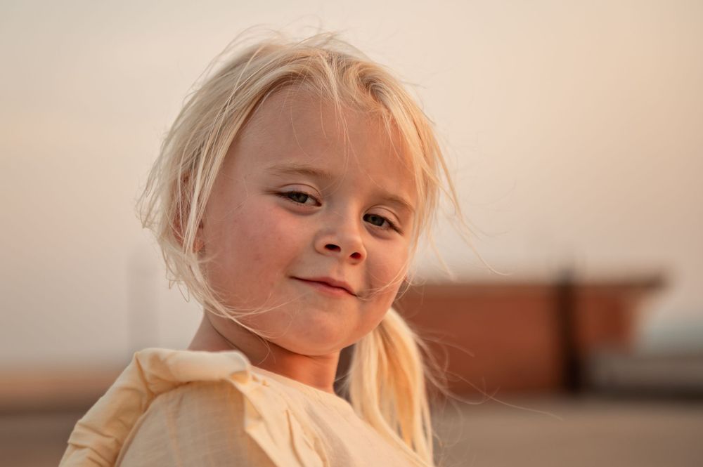 Portrait of a young child in golden light wearing a cream colored top.