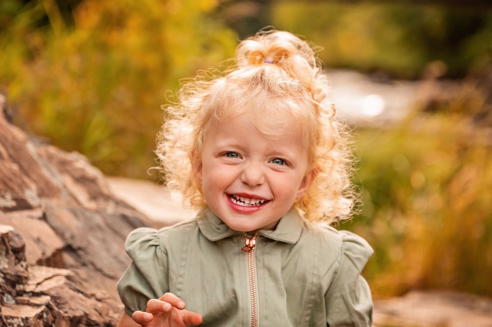 Autumn outdoor portrait session with golden sunlight and natural rock formations.