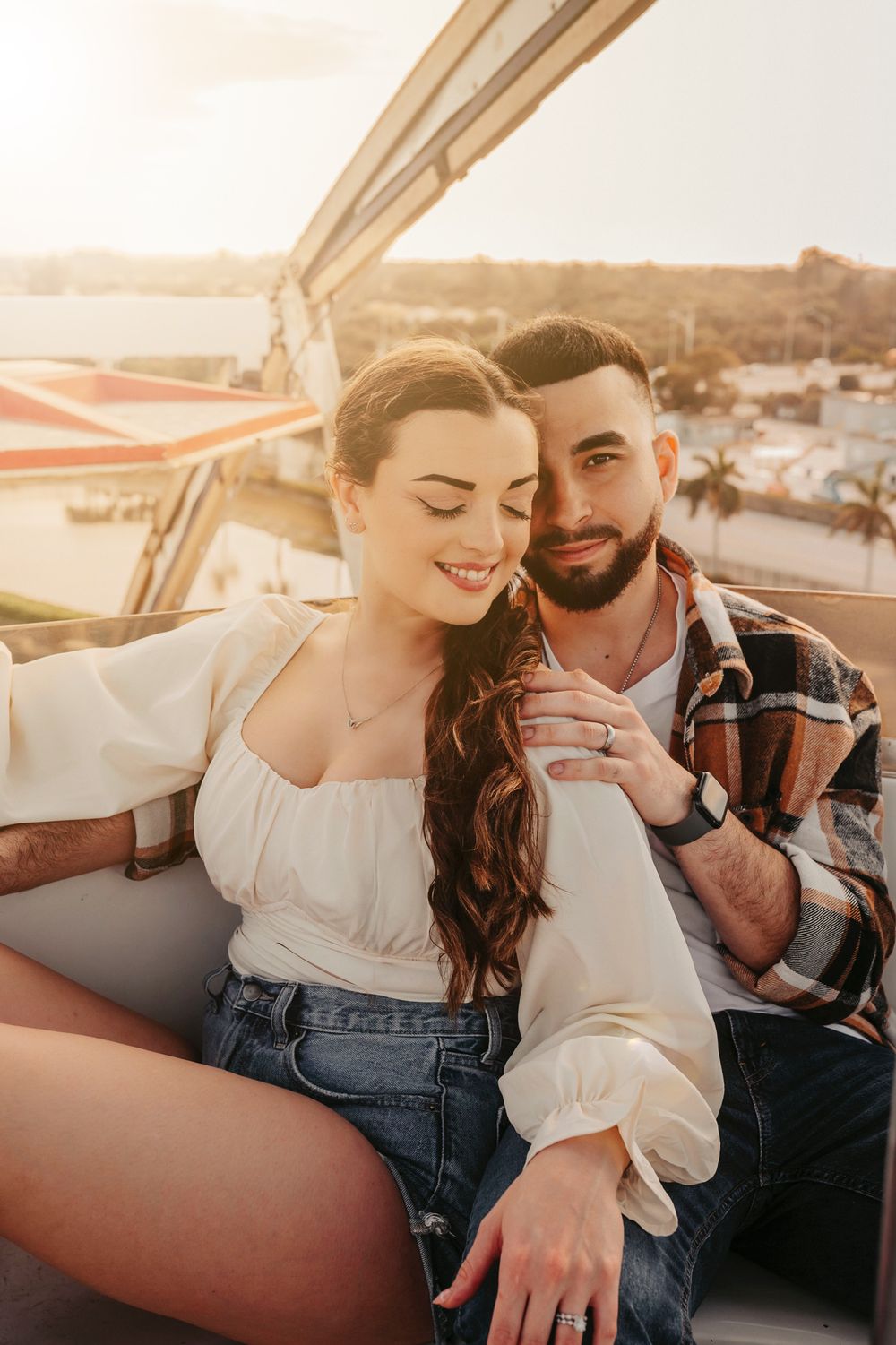 Smiling couple sitting together on a Ferris wheel gondola at golden hour.