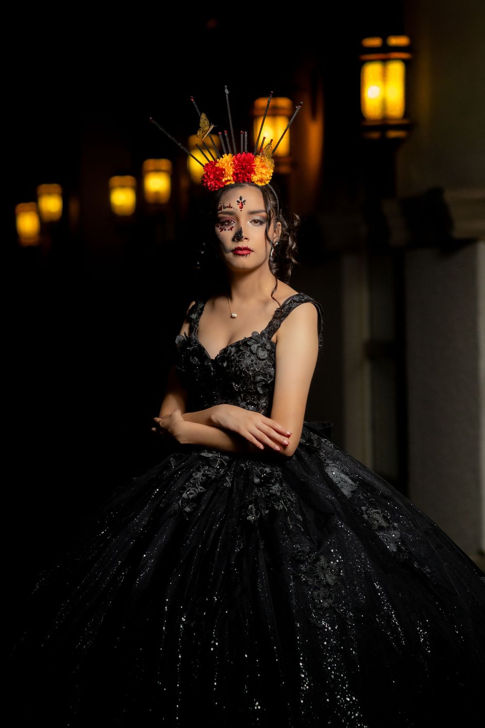 Elegant black ball gown with sparkles photographed in moody dia de los muertos  lighting with lanterns.