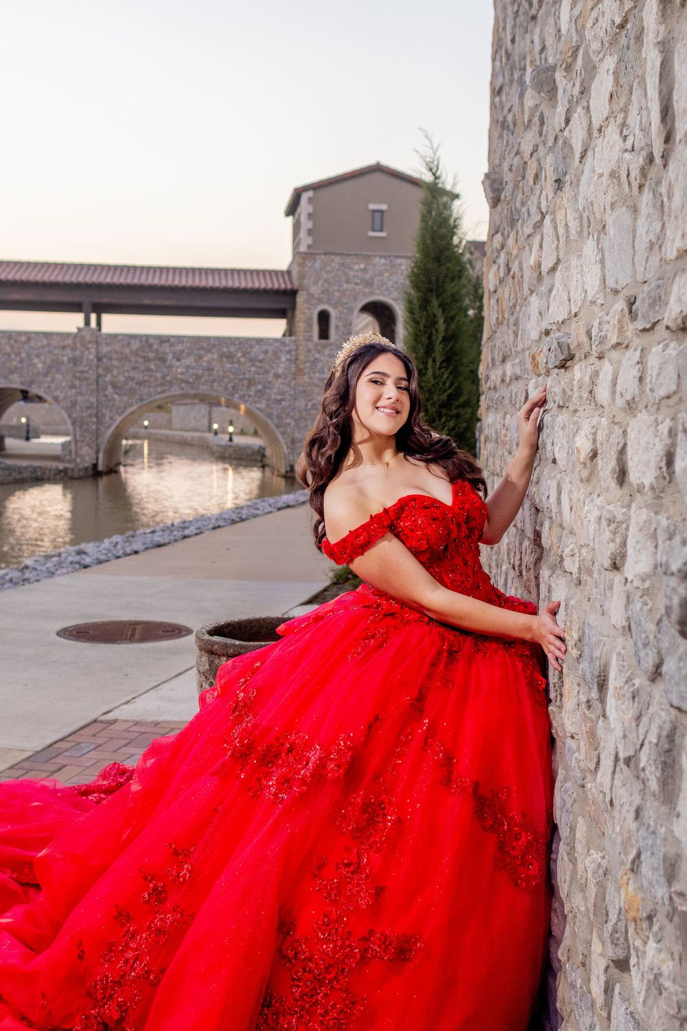 A glamorous red sequined gown captured in an outdoor stone courtyard setting.