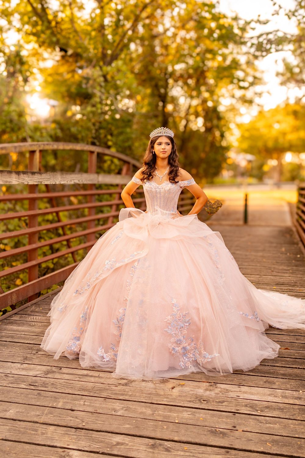 Blush pink quince gown with lace details photographed on wooden bridge at golden hour.