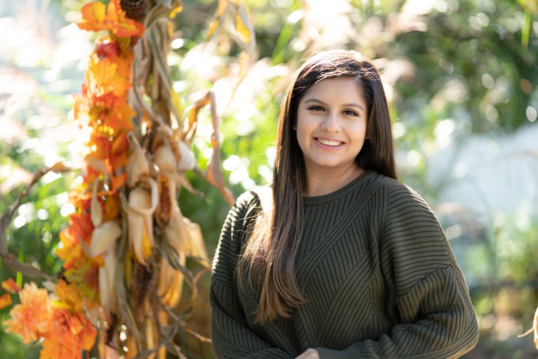 Autumn portrait with orange foliage and green sweater in natural lighting.
