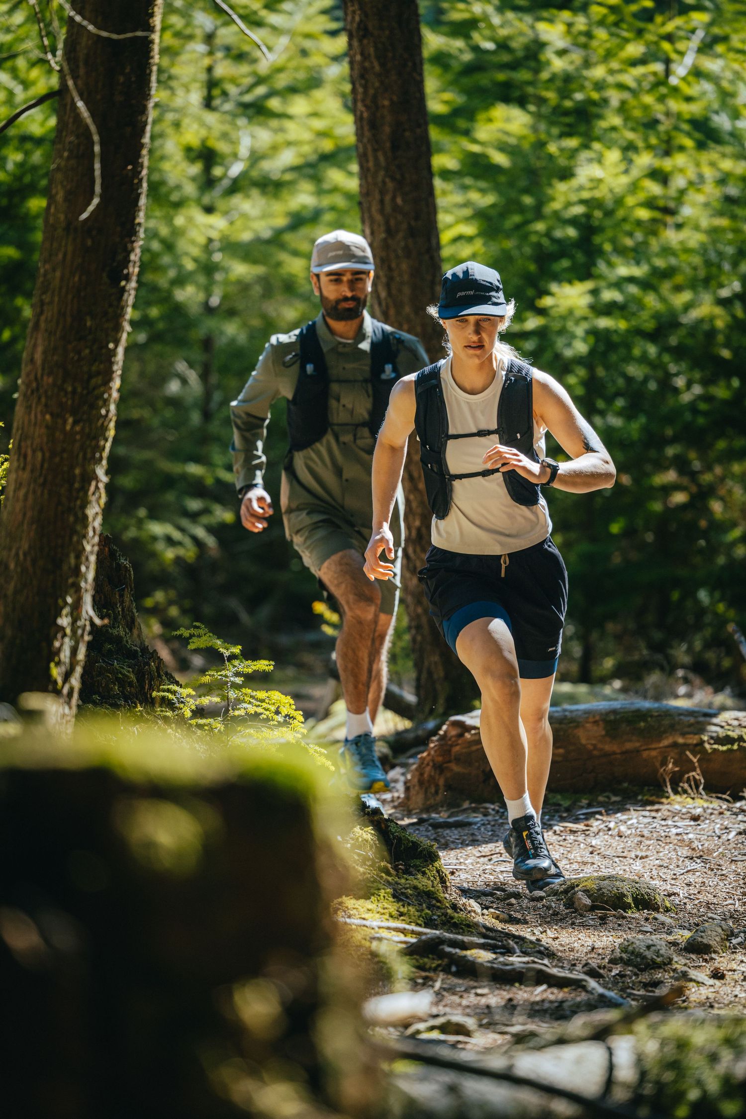 Two hikers walking along a forested trail on sunny afternoon.