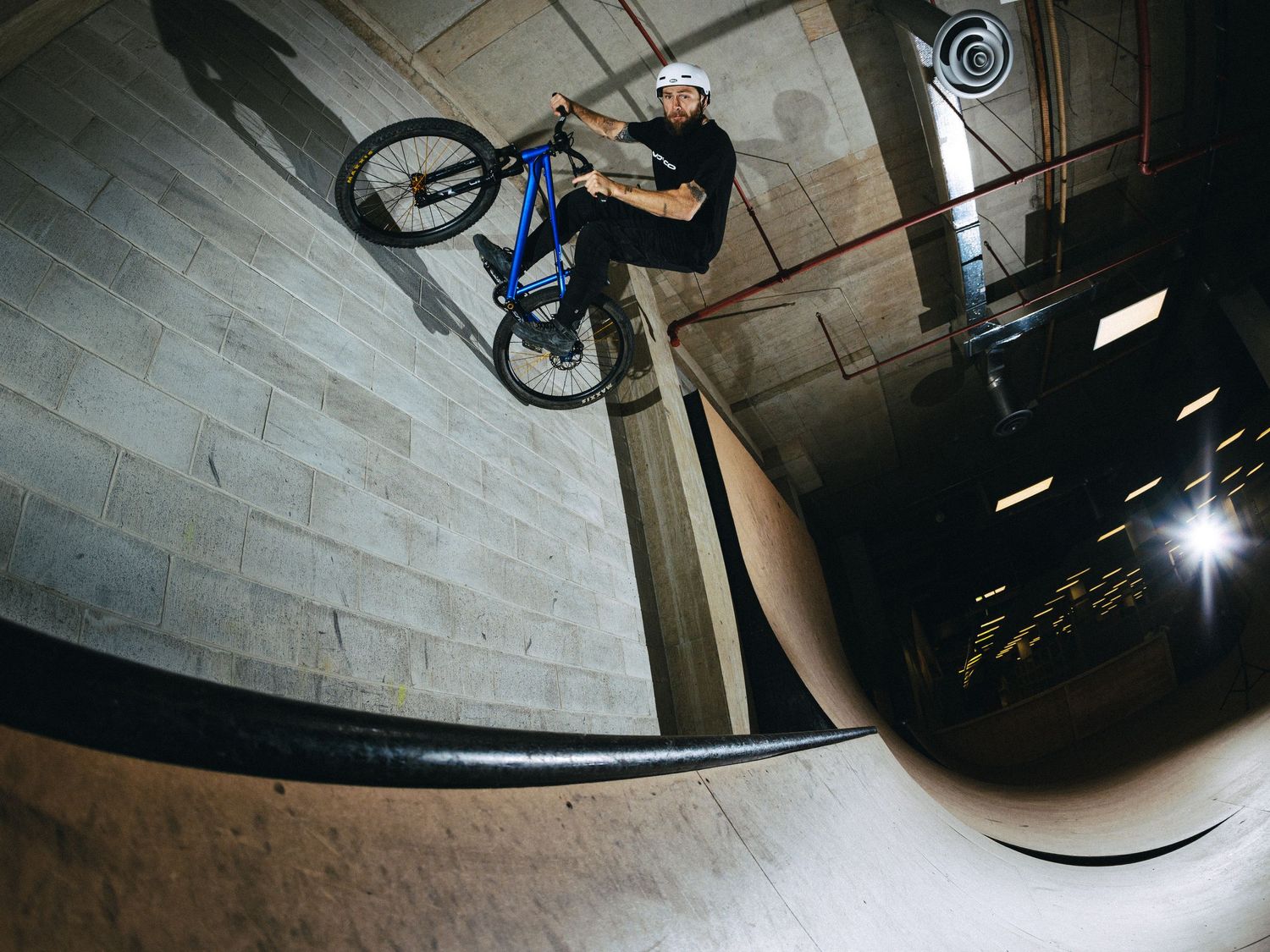 Matt MacDuff performs a wall ride stunt on a brick wall at an indoor bikepark in North Vancouver BC.