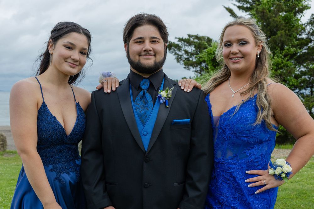 Wedding party in blue and black formal attire posing outdoors.