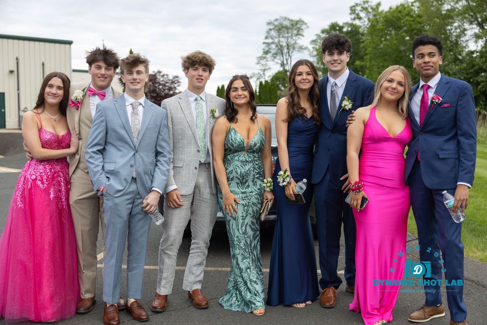 Group photo of people in formal attire including bright pink dresses and gray suits at a special event.