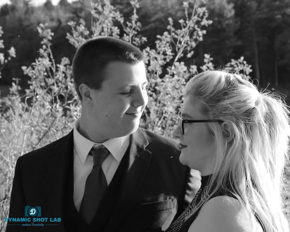 A couple shares a romantic moment outdoors during a wedding photoshoot with blossoming trees in the background.
