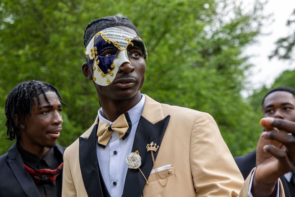 A group poses in formal wear including gold jackets and bow ties in an outdoor setting.
