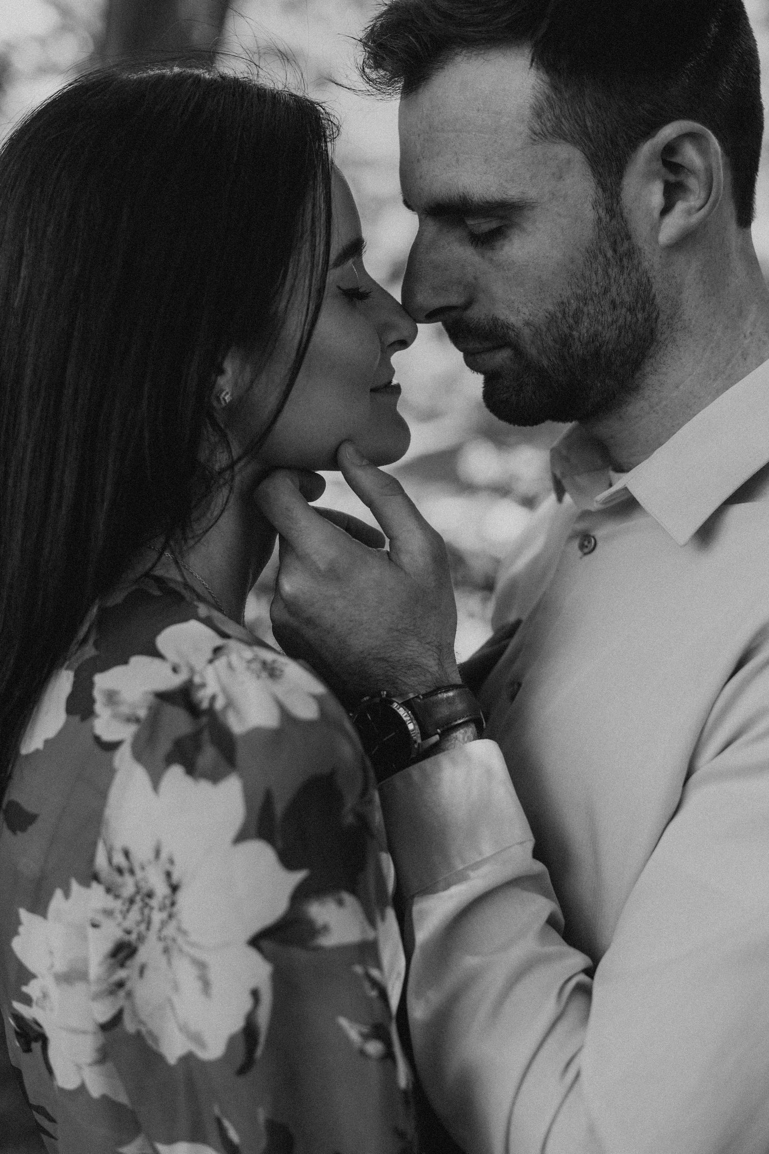 An intimate black and white portrait showing a tender moment between two people.