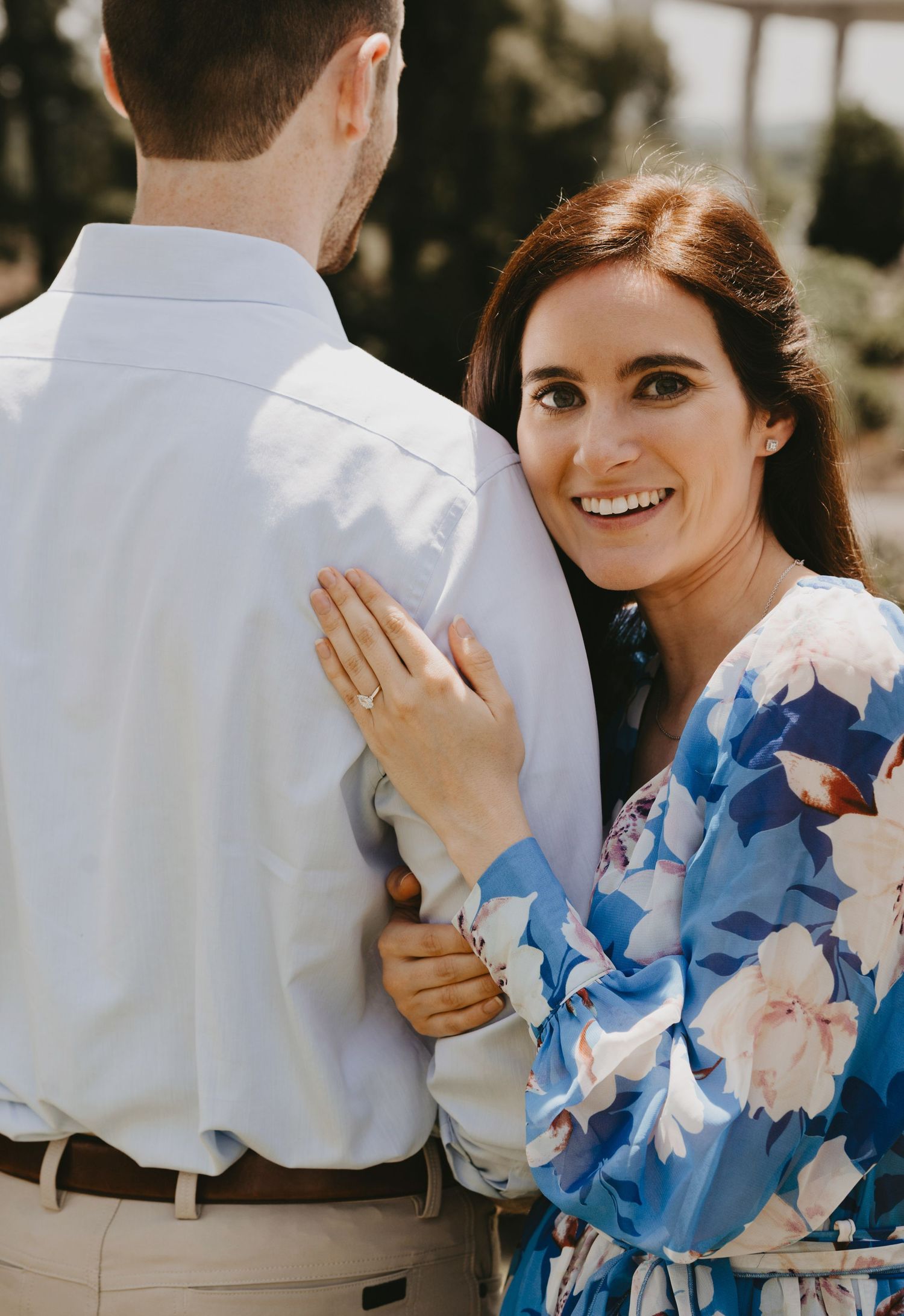 A romantic moment captured in natural light with a blue floral dress and white shirt.