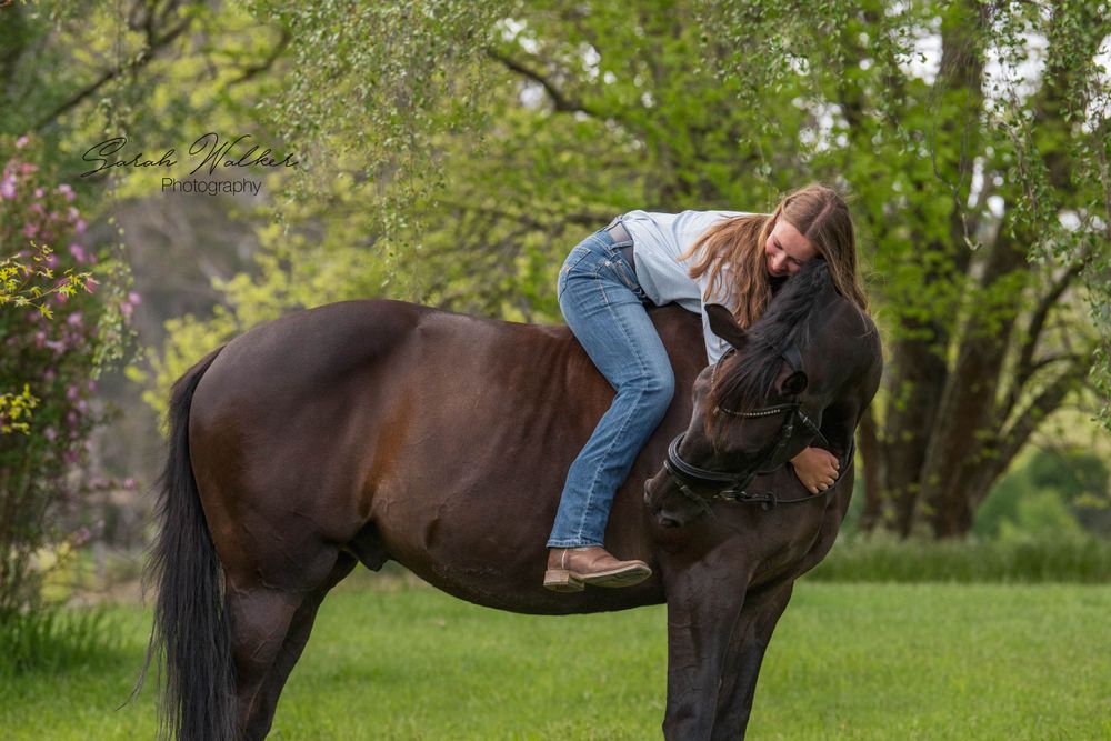 A horse and rider enjoy a sweet moment in an outdoor grassy field.
