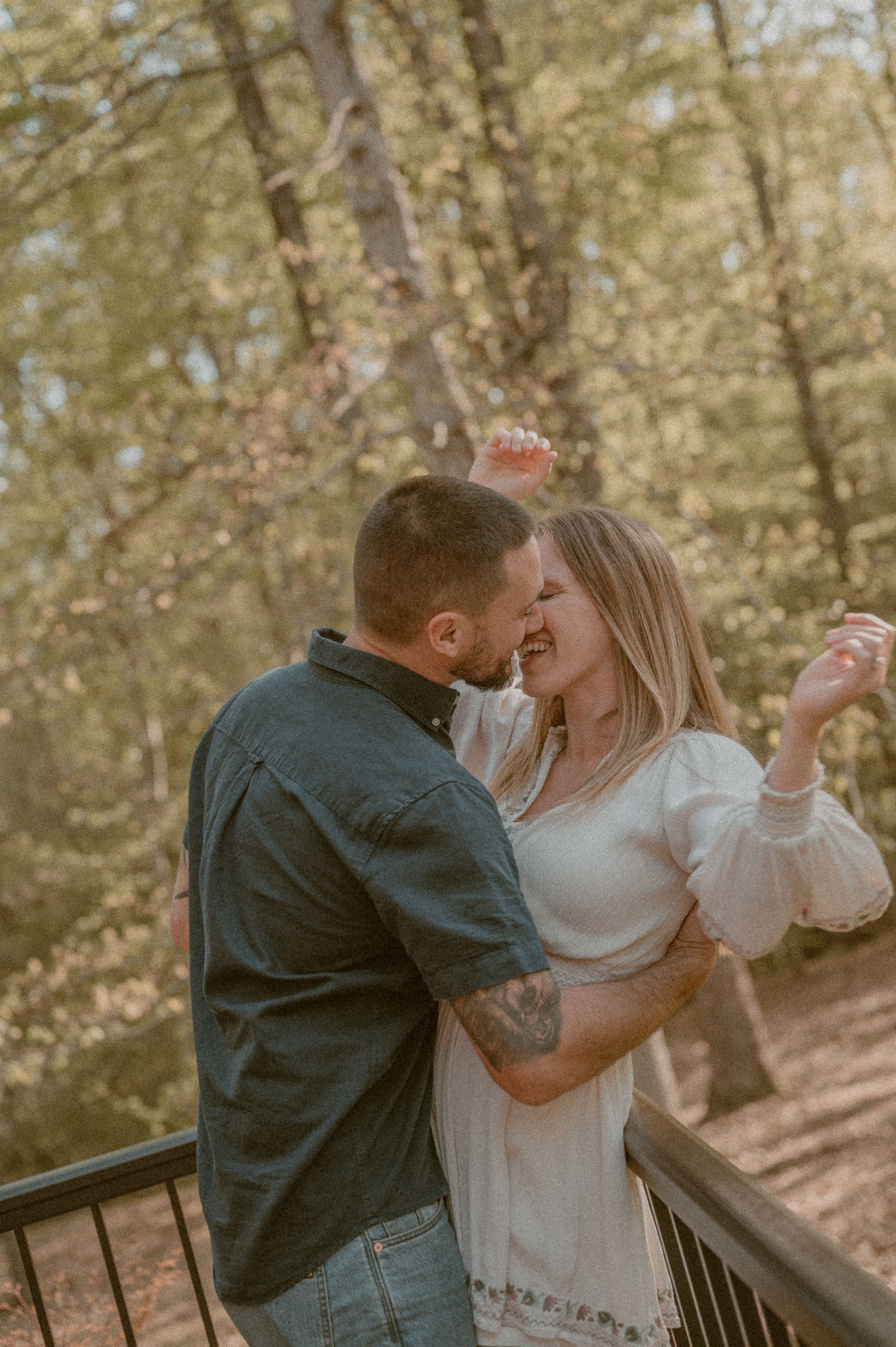 A romantic golden hour moment showing a couple dancing and embracing on a wooden deck surrounded by trees.