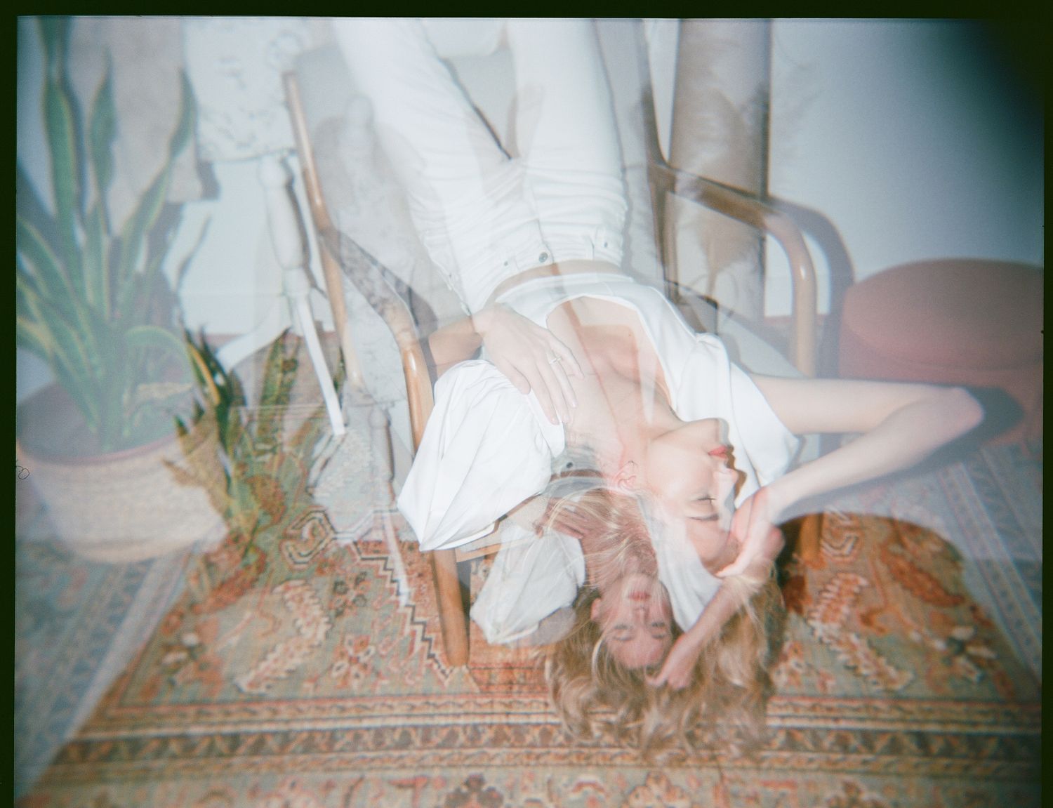 Dreamy vintage-style photograph of white dress flowing against patterned carpet.