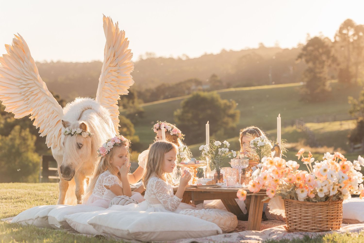 Elegant outdoor setup with white decorations and flowers at sunset.