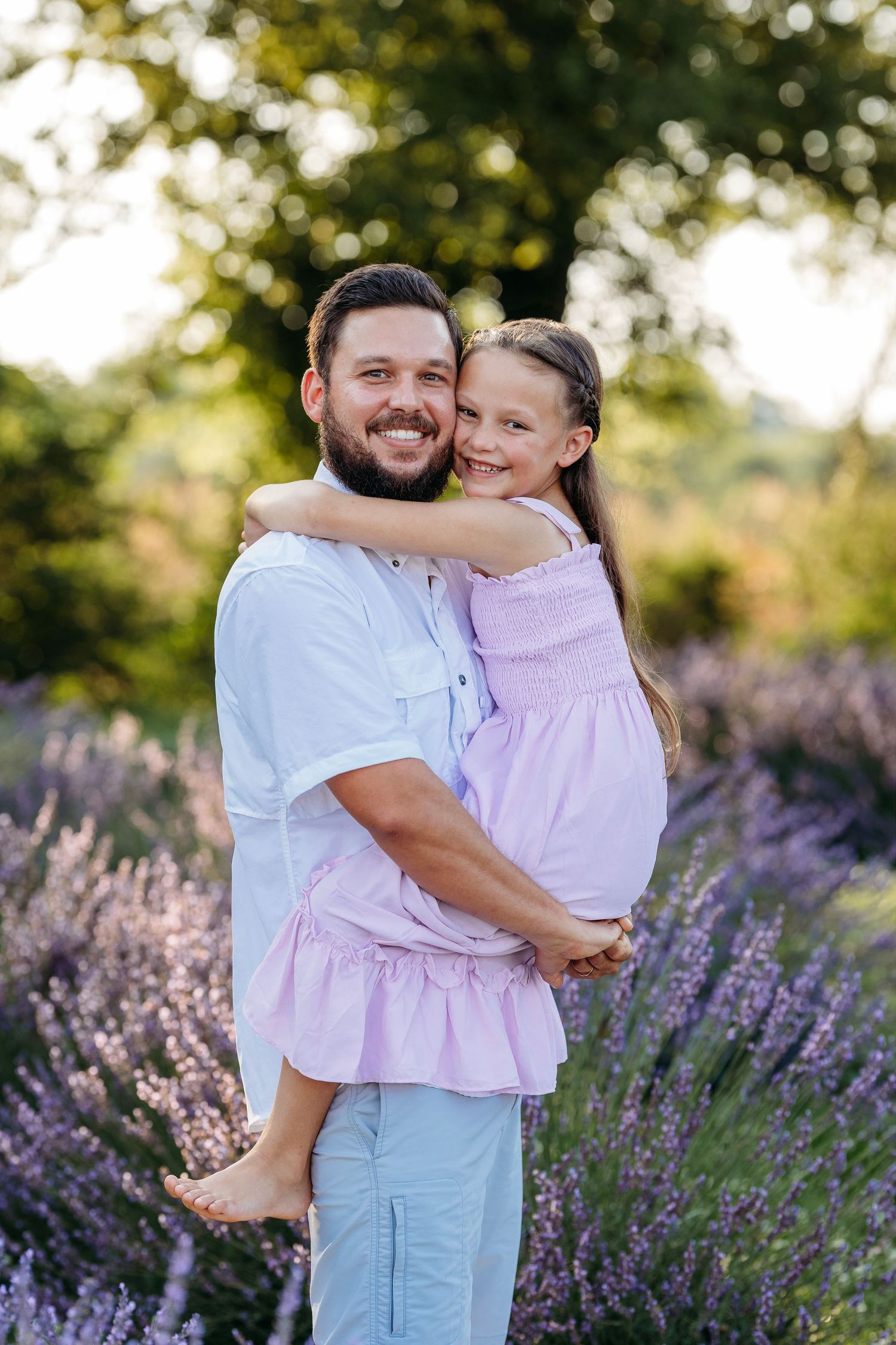 A dad and daughter embrace in a blooming lavender field on a sunny summer day. Middle Tennessee Best Family Photographer