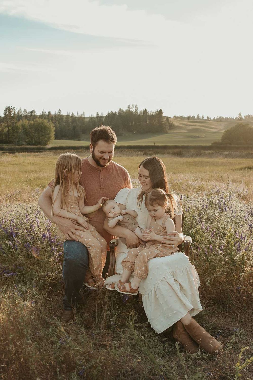 family sitting in a flower field in spokane looking at their baby