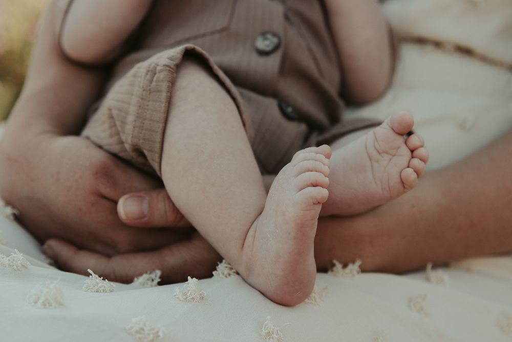 close up of baby feet while being held by mom in white dress by spokane family photographer
