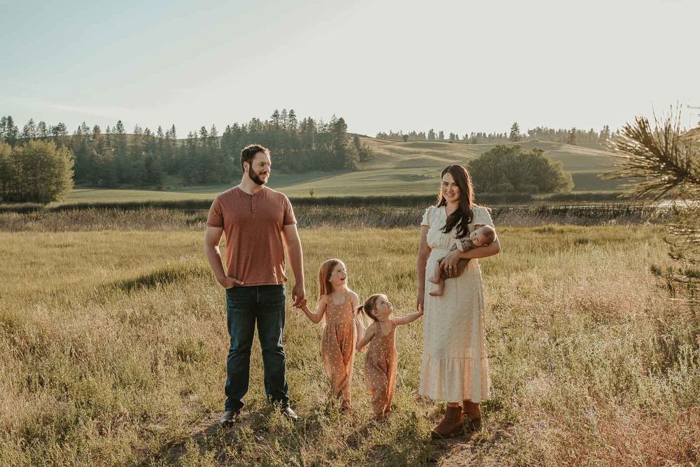 family of five in spokane holding hands and looking towards the mom all wearing earth tone outfits