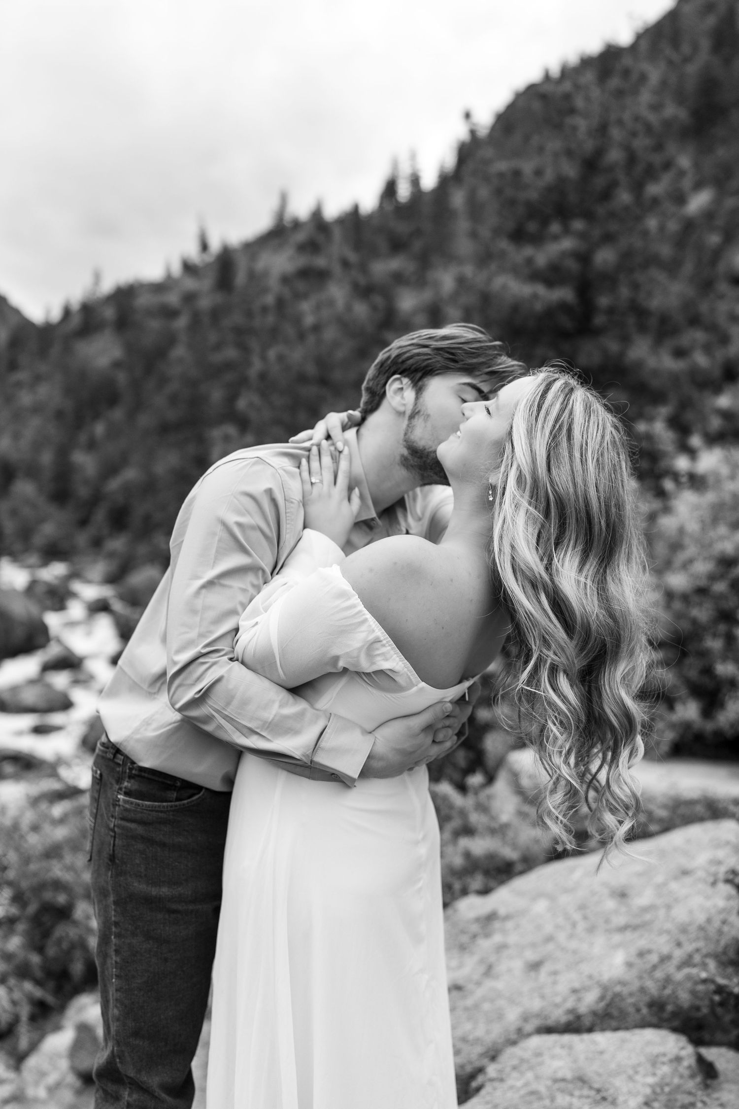 A romantic moment captured in black and white against a mountainous backdrop.