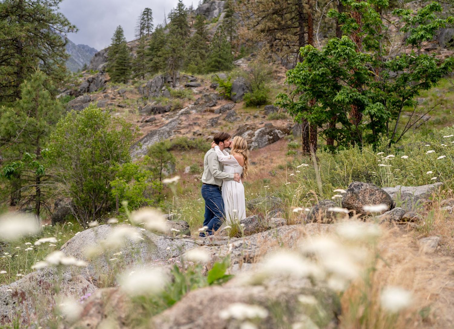 A couple embracing on a scenic mountain trail surrounded by wilderness.