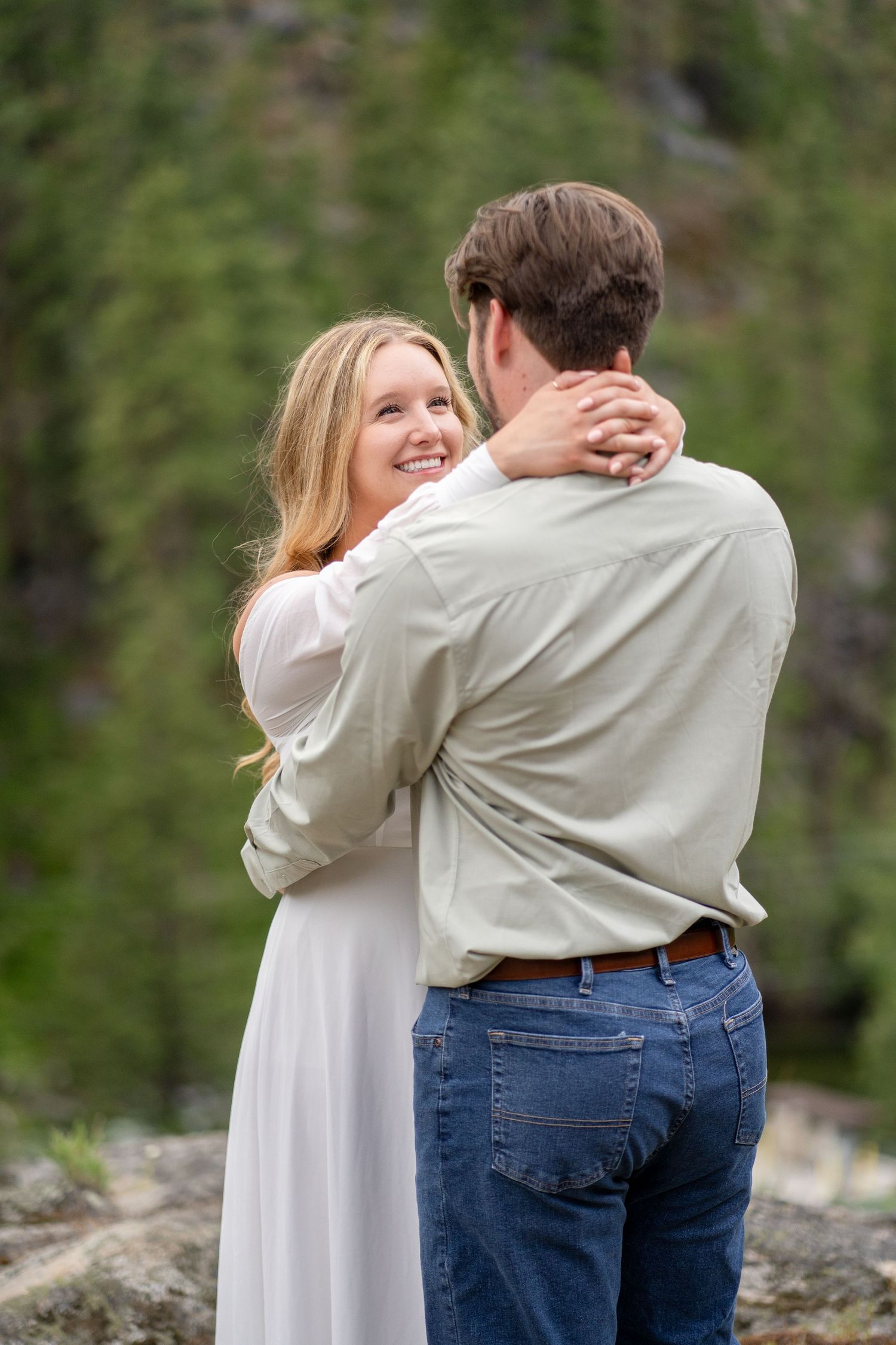A tender embrace captured against a forested mountain backdrop.
