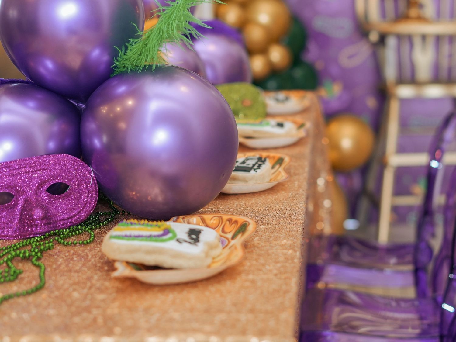 Close-up of party decorations with purple and gold balloons against a sparkly sequin tablecloth.