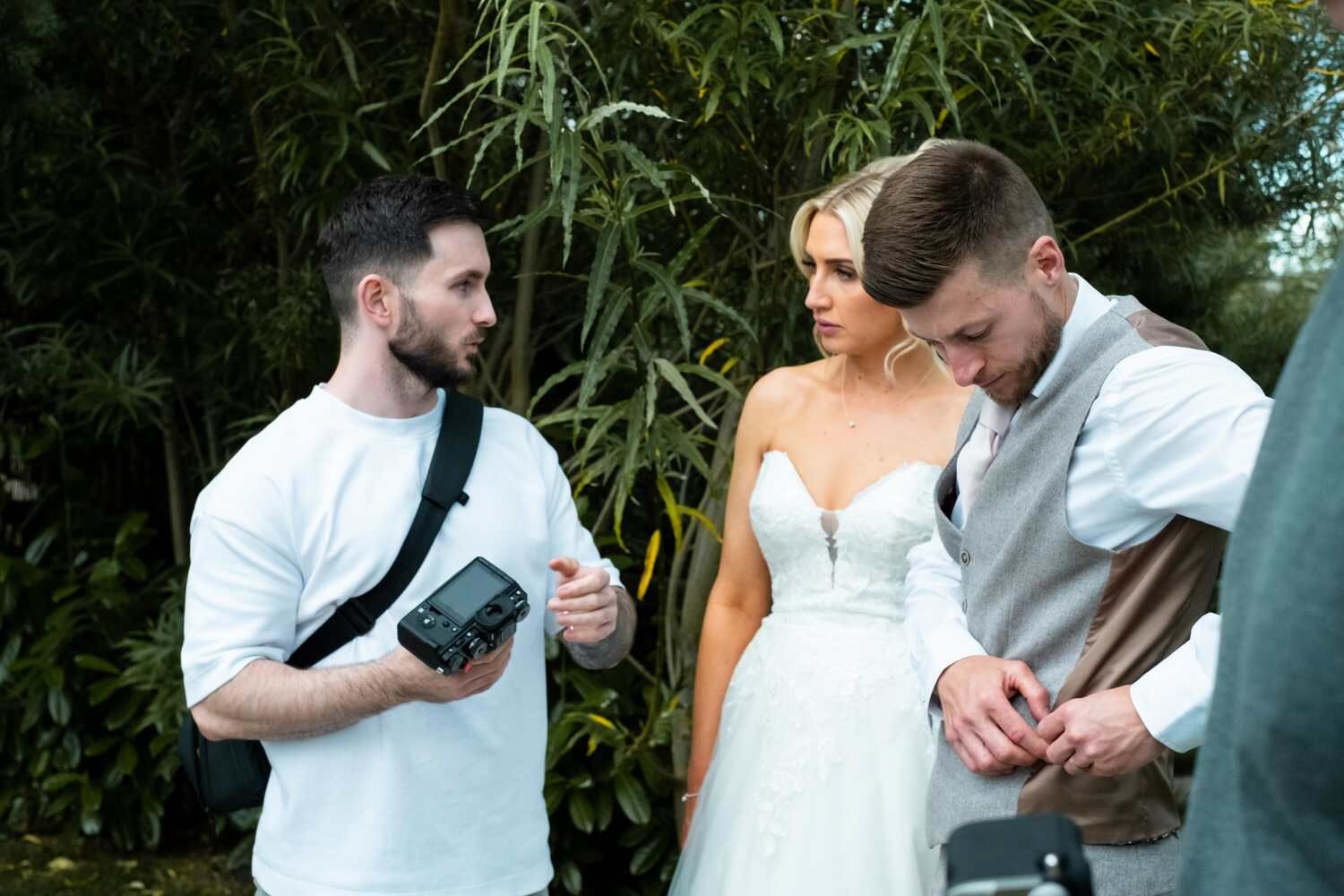 A candid moment with the bride and groom receiving guidance from a photographer.