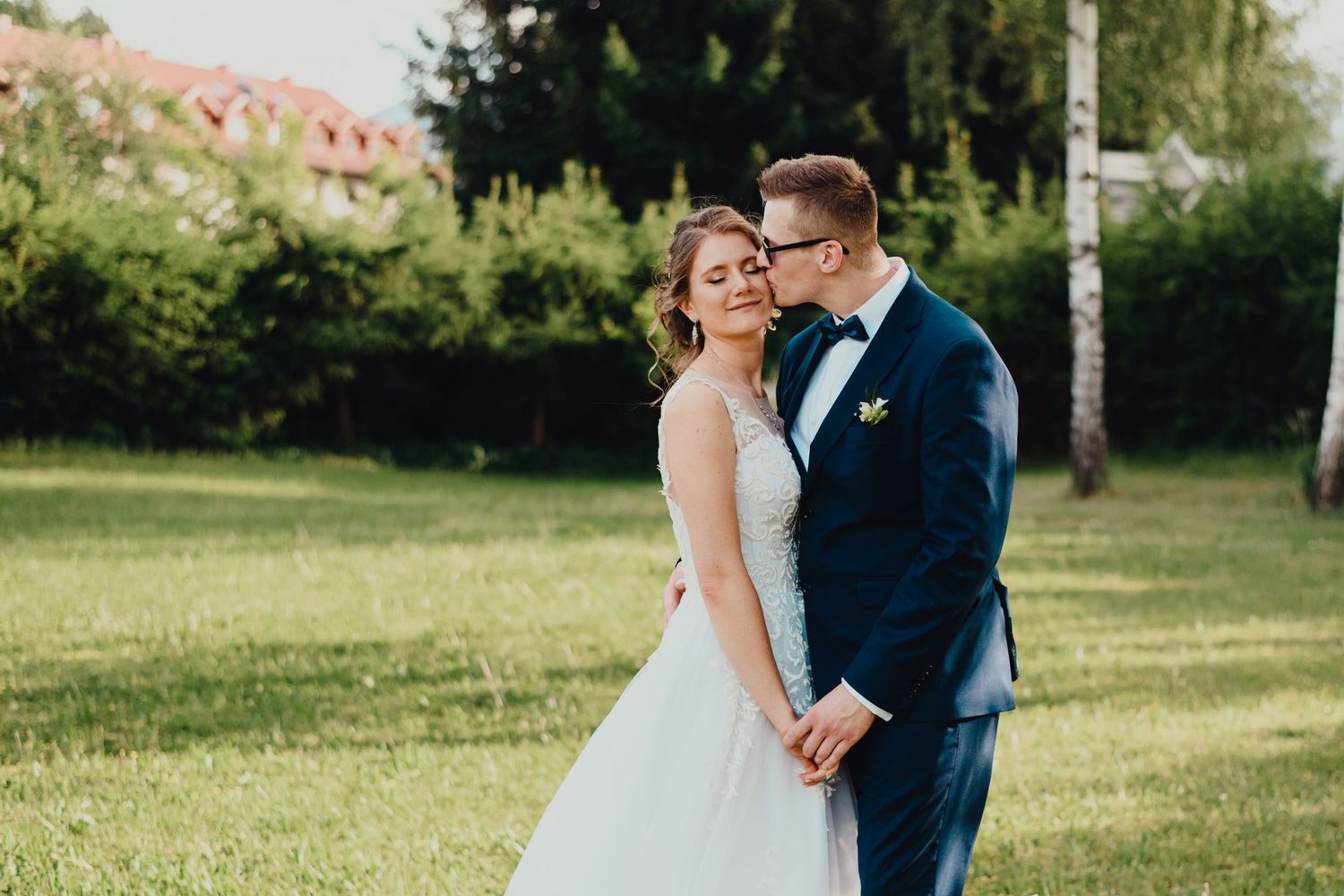 A newlywed couple shares a romantic moment in a sunny garden setting.