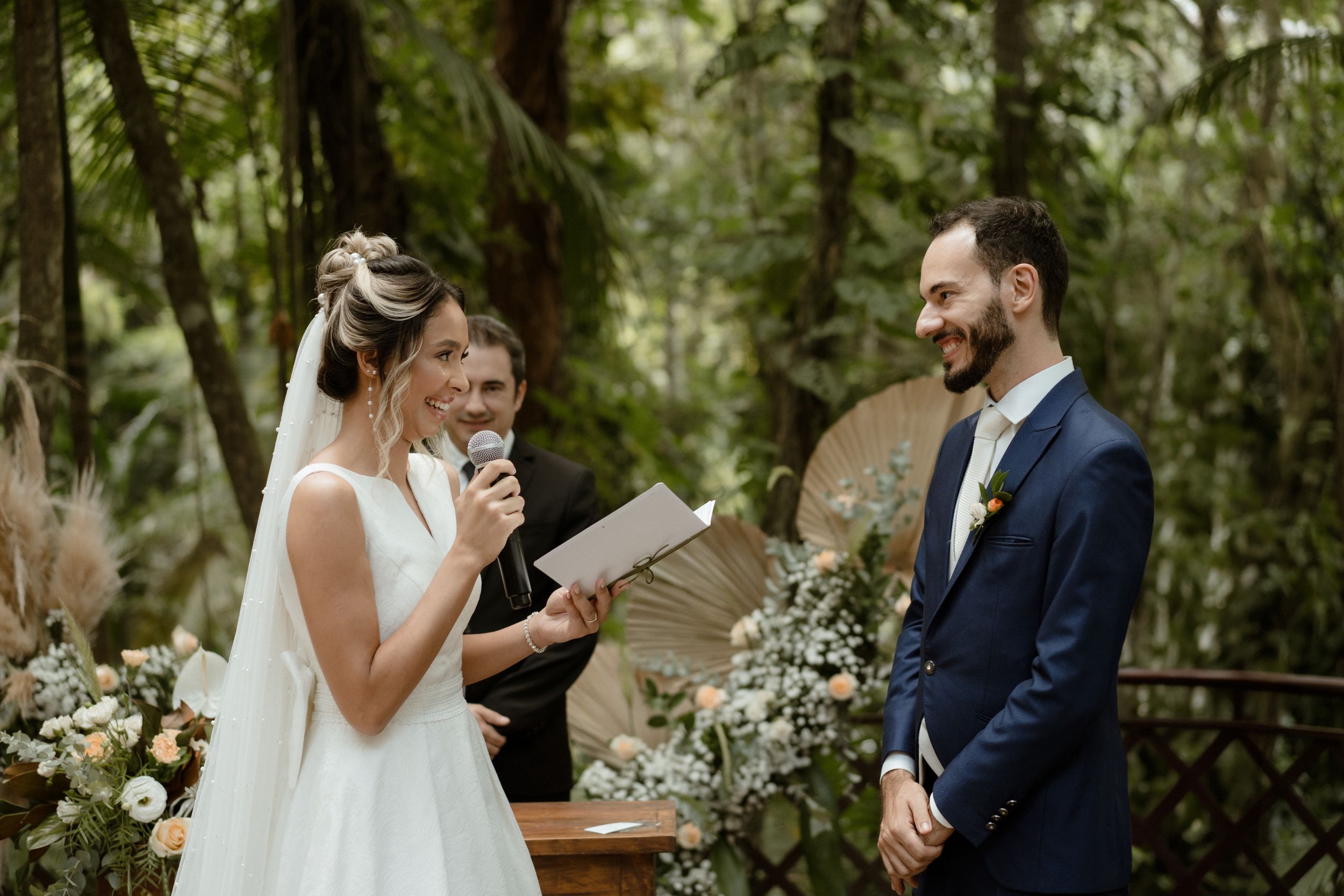 A wedding ceremony in progress amidst a forest setting with floral decorations.