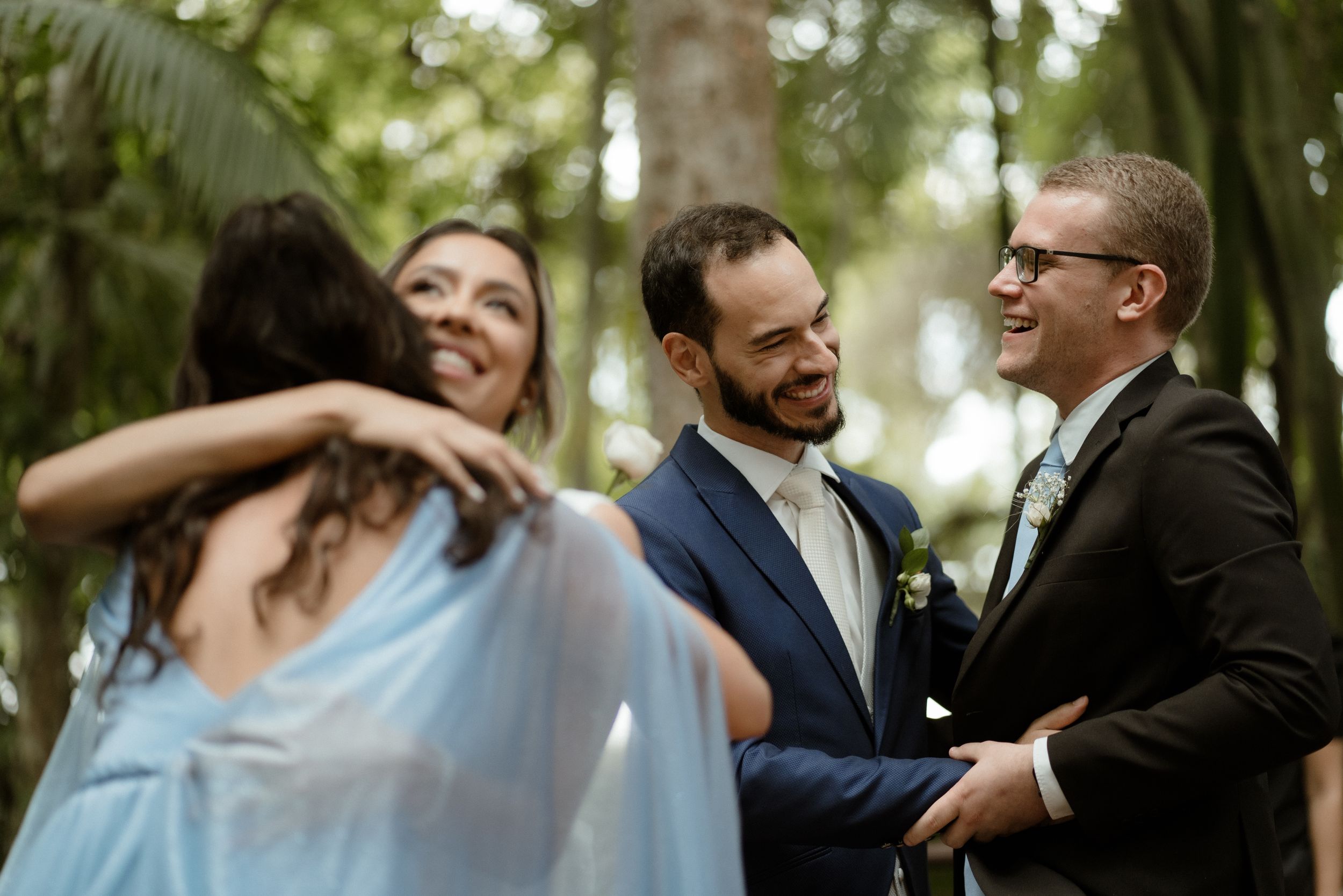 Wedding party celebrating and laughing together in a lush forest setting.