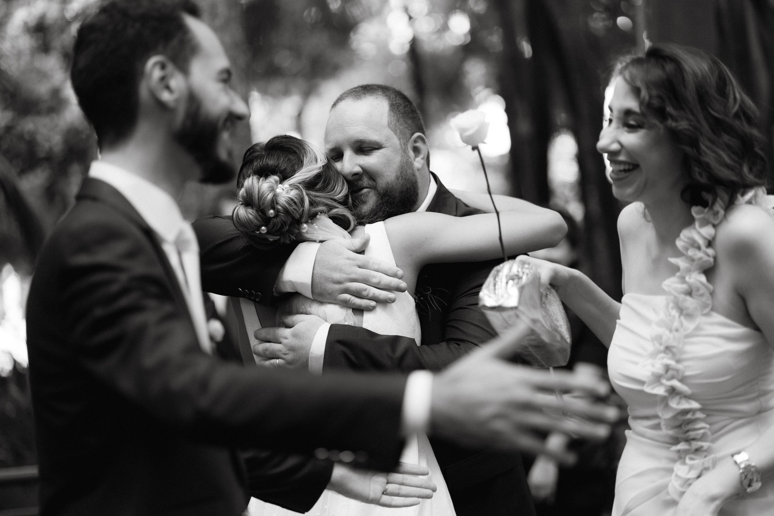 Black and white candid photo of joyful celebration during wedding reception.
