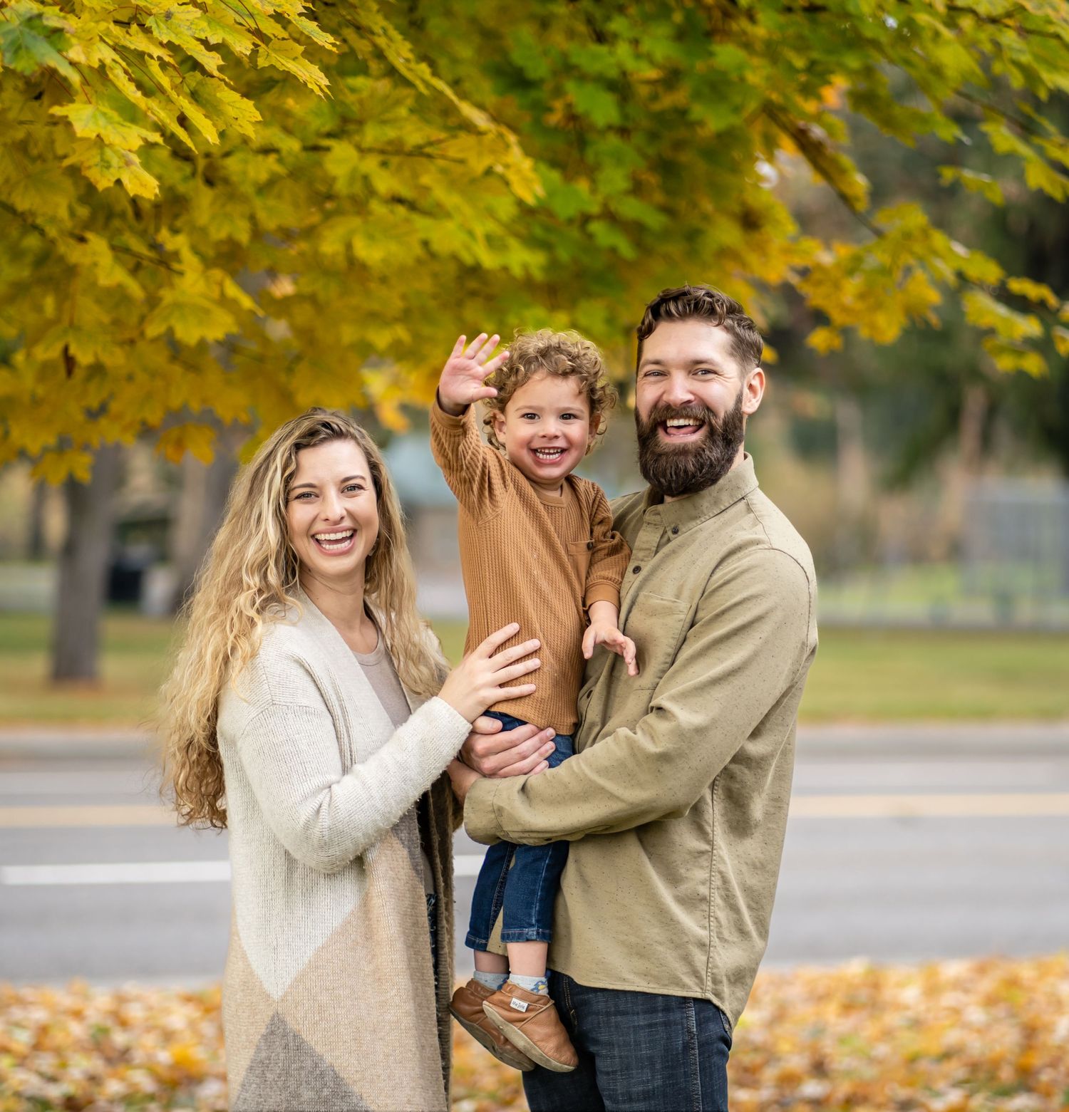 Happy family enjoying an autumn day with yellow leaves and trees in the background.