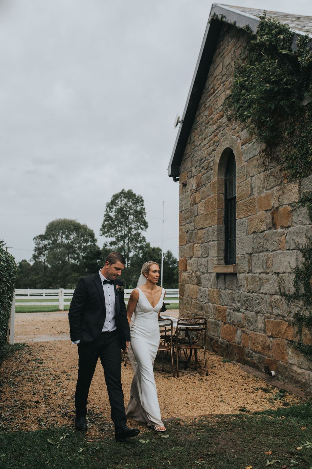 Couple poses against rustic stone church wall exterior during wedding portraits.
