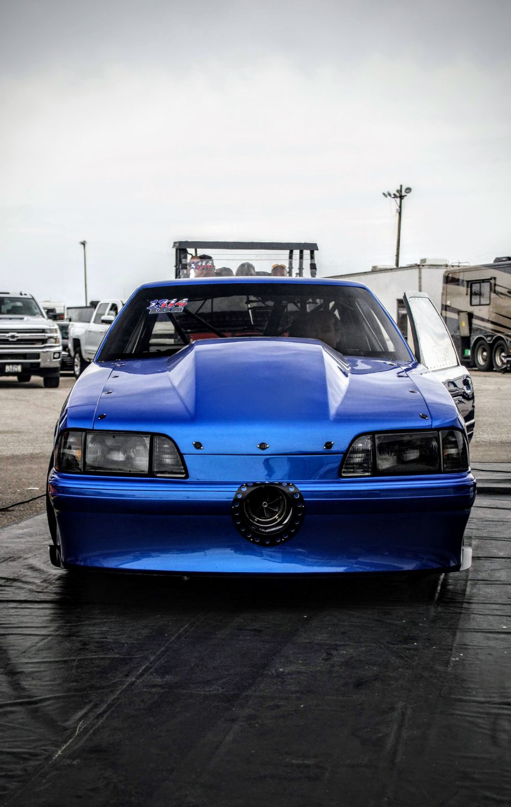Front view of a bright blue drag racing car with custom modifications and aerodynamic features.