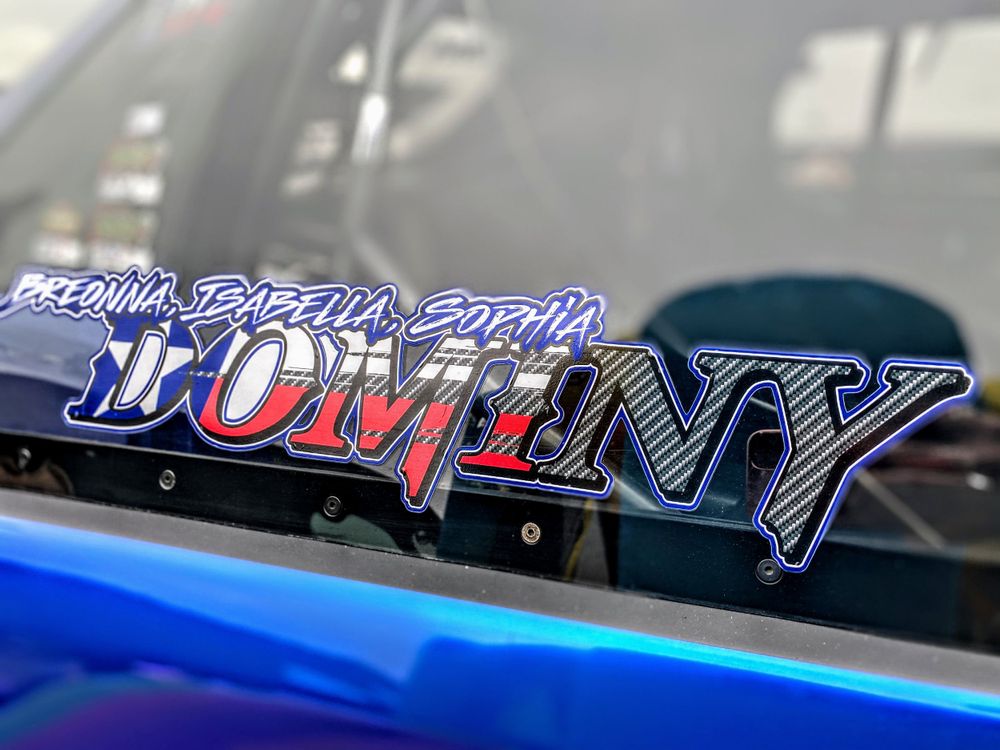 Close-up of a custom Dominy racing decal in blue and red gradient lettering.