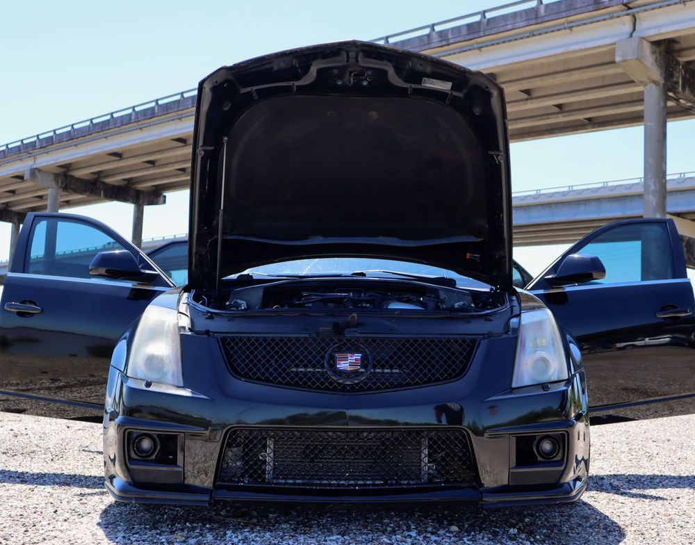Front view of a black Cadillac CTS-V with hood open showing engine bay.