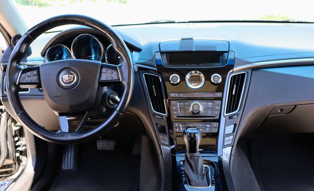 Modern luxury car interior dashboard with digital displays and leather steering wheel.