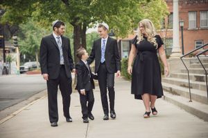 Family of four walking together on sidewalk dressed in formal attire.