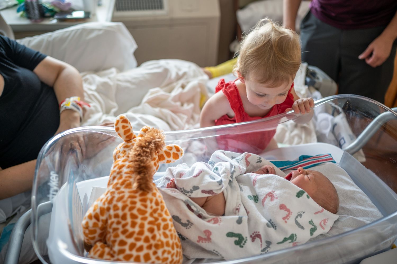 Toddler leaning over baby newborn bassinet in hospital fresh 48 photoshoot candid moment Brevard Melbourne Cocoa Beach Vero Florida